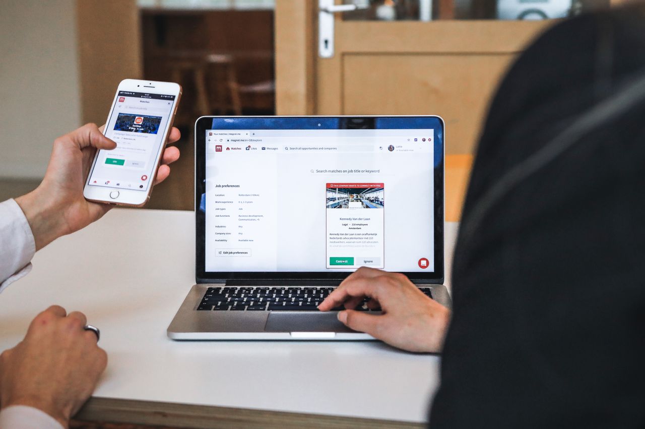 Bolwate solution Hands using smartphone and laptop for digital browsing in an office setting, showcasing remote work culture.